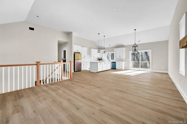 a view of a electric appliances in kitchen and empty room with wooden floor
