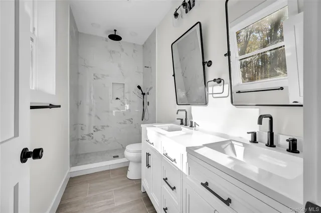 a bathroom with a double vanity sink toilet and shower