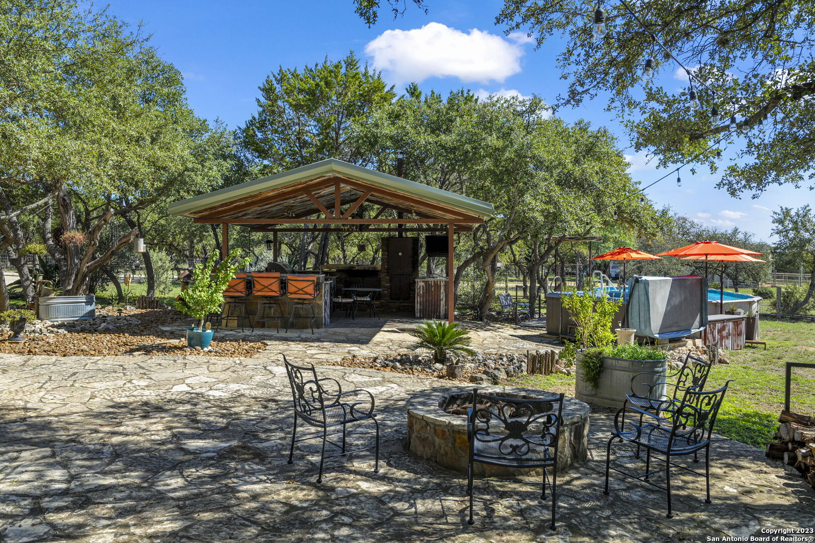 849 Madrona Ridge Drive Bandera, TX 78003 - Photo 10 of 44 a view of a patio with table and chairs under an umbrella with large trees