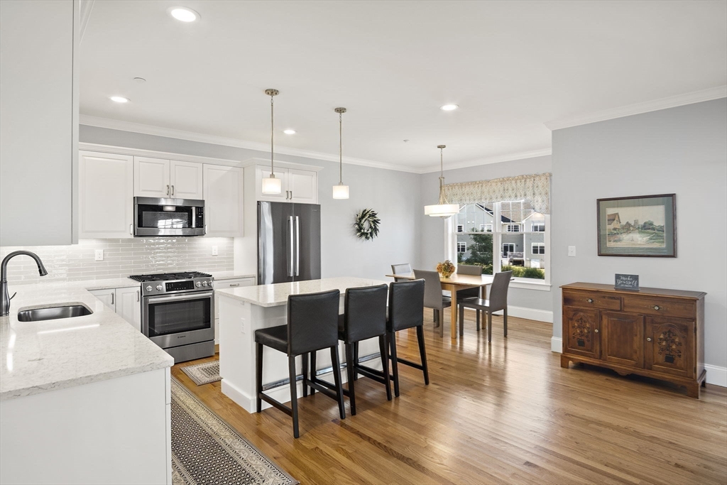 8 Winning Farm Road, Unit 8 Woburn, MA 01801 - Photo 3 of 42 a kitchen with stainless steel appliances granite countertop a stove top oven a sink dishwasher a dining table and chairs with wooden floor