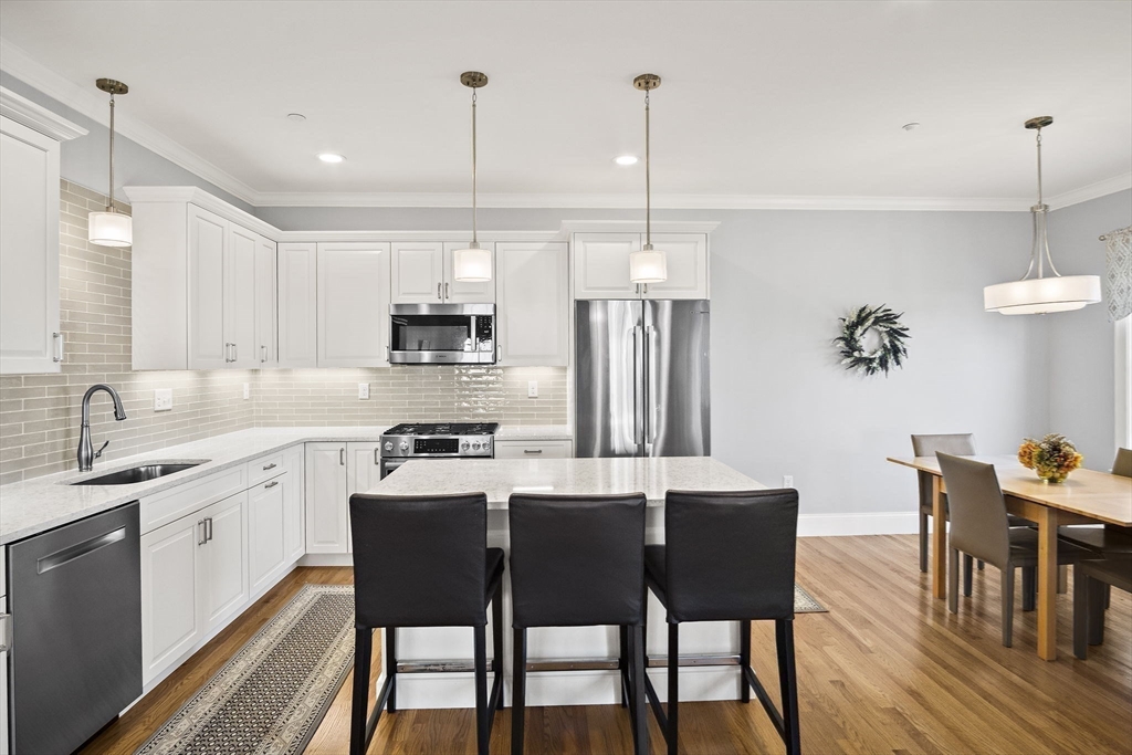 8 Winning Farm Road, Unit 8 Woburn, MA 01801 - Photo 5 of 42 a kitchen with stainless steel appliances granite countertop a dining table chairs stove a sink and dishwasher