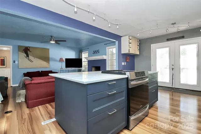 a large kitchen with stainless steel appliances granite countertop a sink dishwasher a stove and a dining table with wooden floor