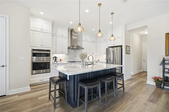 a large kitchen with stainless steel appliances kitchen island granite countertop a table chairs sink and cabinets