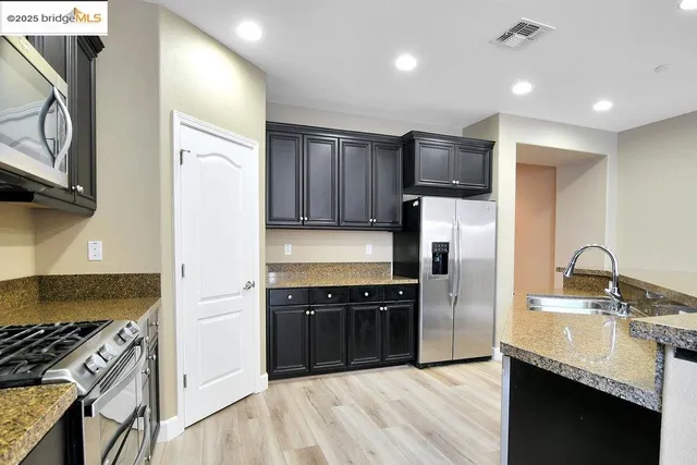 a kitchen with kitchen island granite countertop a sink stainless steel appliances and cabinets