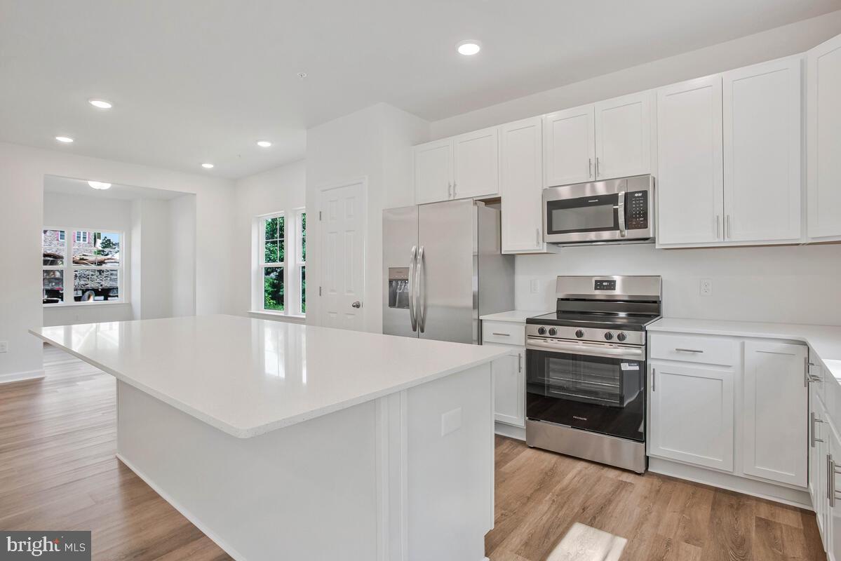 404 Warwick Place Edgewater, MD 21037 - Photo 11 of 76 a kitchen with stainless steel appliances a stove a microwave a sink a refrigerator white cabinets and wooden floor