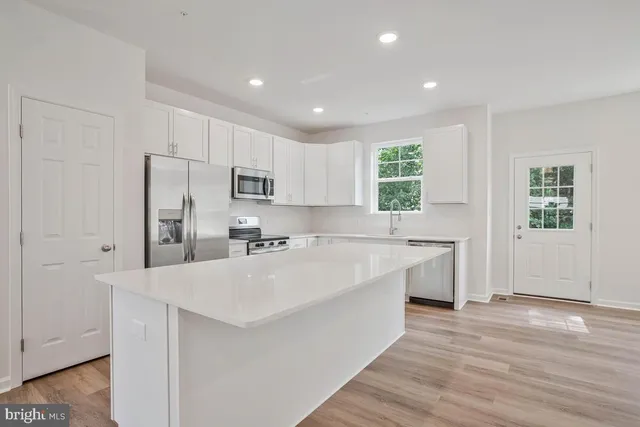 a large white kitchen with granite countertop a sink and dishwasher with a large window