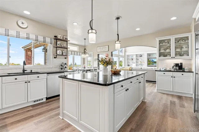 a large kitchen with granite countertop lots of white cabinets and wooden floor