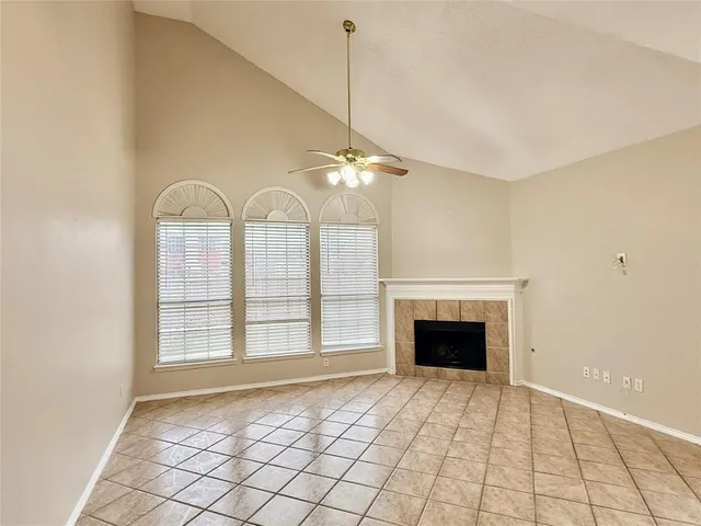 a view of an empty room with window and chandelier fan