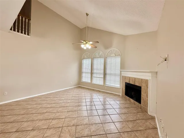 a view of an empty room with chandelier fan and fire place
