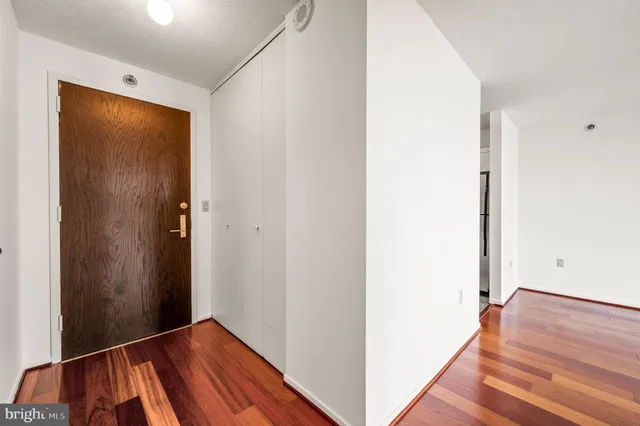 a view of an empty room with wooden floor and closet
