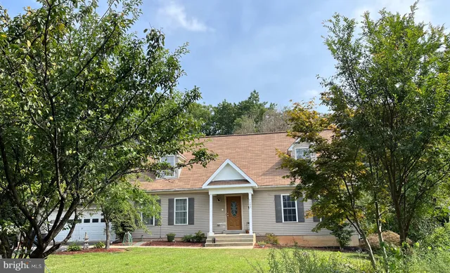 a front view of a house with garden and trees
