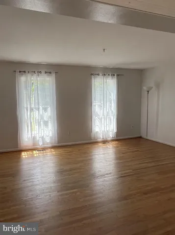 an empty room with wooden floor and windows with curtains view