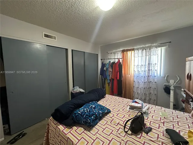 a bed room with a bed a couch and a flat tv screen on a dresser