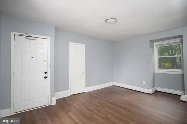 a view of an empty room with wooden floor and a window