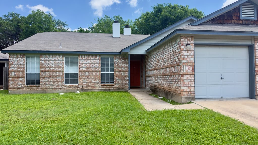 2306 Fuzz Fairway, Unit A Austin, TX 78728 - Photo 2 of 20 Brick facade home featuring a single-car garage, multiple windows, and a red entry door