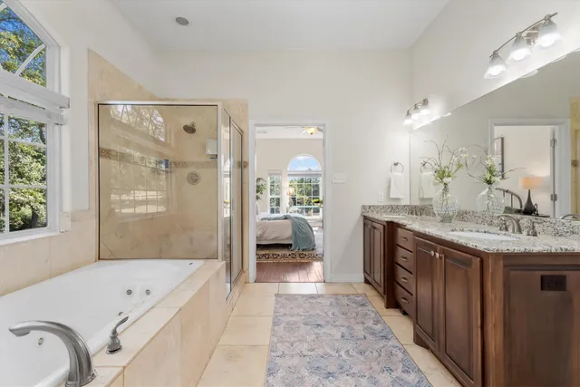 a spacious bathroom with a granite countertop tub sink a mirror a shower and a bathtub