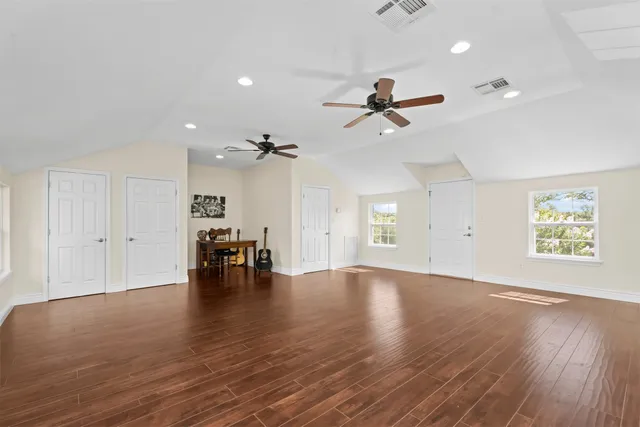 an empty room with wooden floor and ceiling fan
