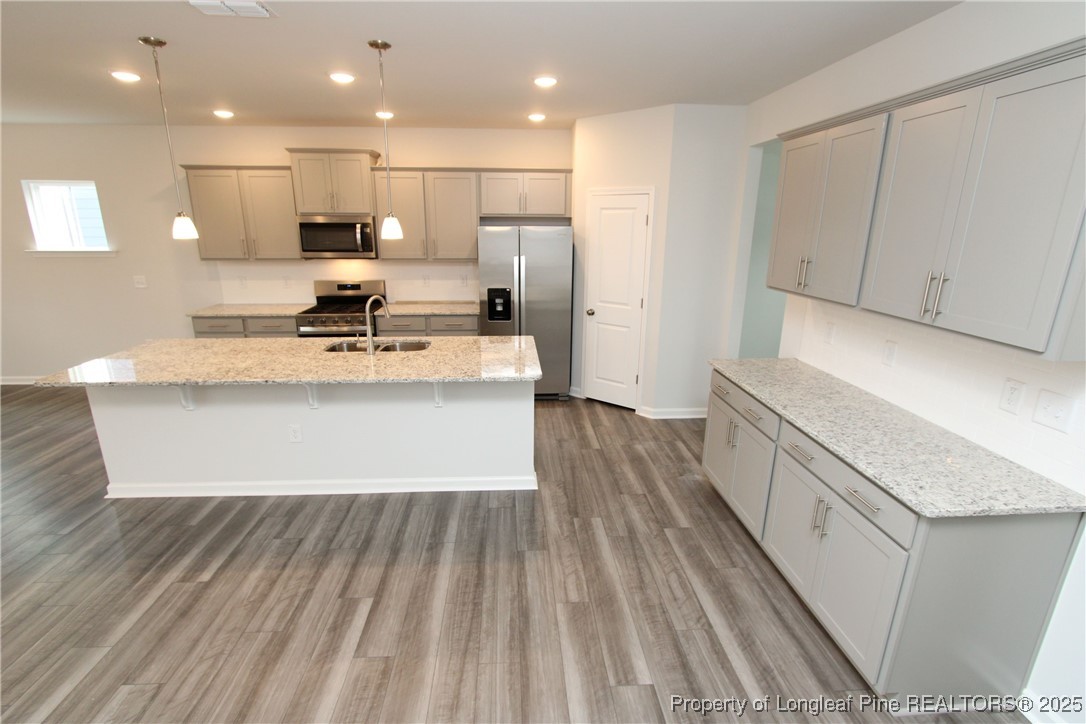 461 Grange Farm Place Raleigh, NC 27603 - Photo 10 of 50 a large white kitchen with wooden floors and stainless steel appliances