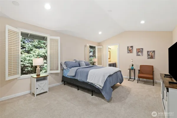 a spacious bedroom with a large bed and a flat tv screen on dresser