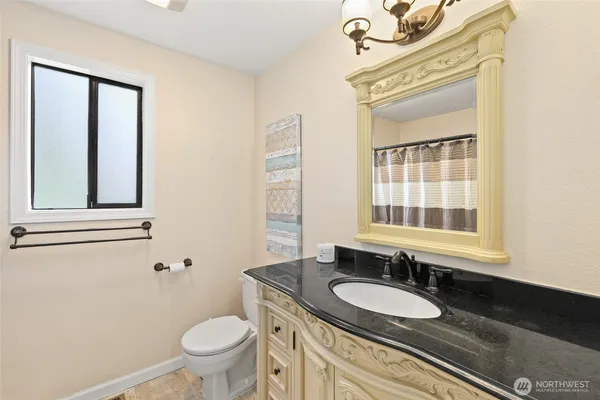 a bathroom with a granite countertop toilet a sink and a mirror
