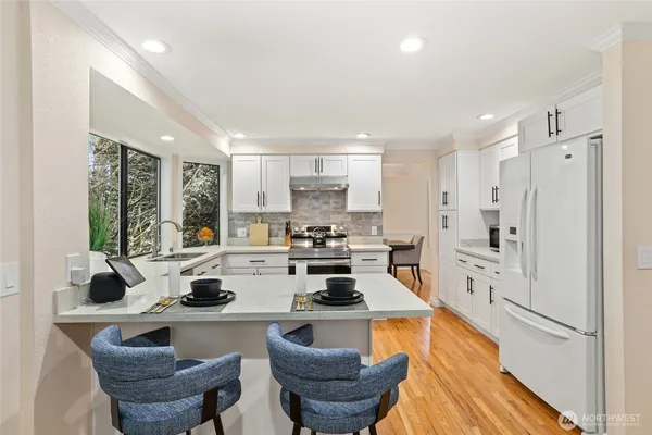 a kitchen with stainless steel appliances granite countertop a stove a sink a refrigerator and white cabinets