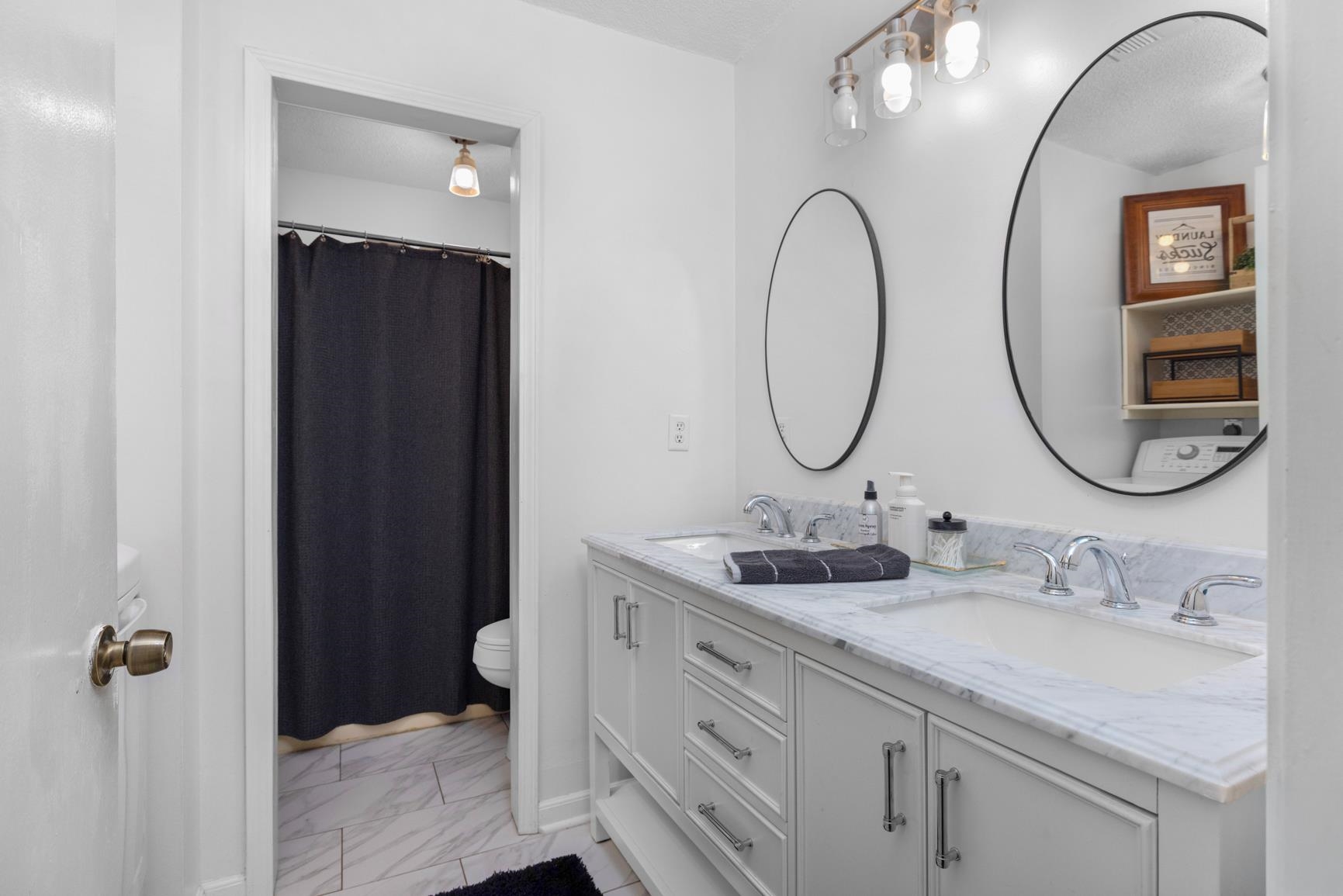 586 Beaver Road Munford, TN 38058 - Photo 12 of 21 Double vanity with white cabinetry and chrome hardware, featuring a light-toned stone-finish countertop and two integrated sinks