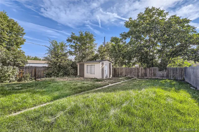 a view of a backyard with large trees and wooden fence
