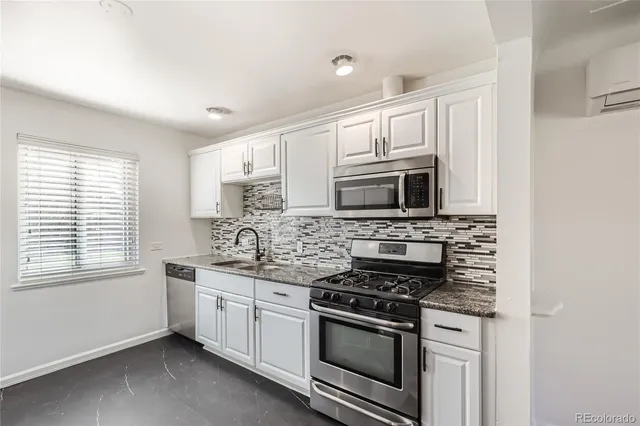 a kitchen with stainless steel appliances white cabinets and a stove top oven