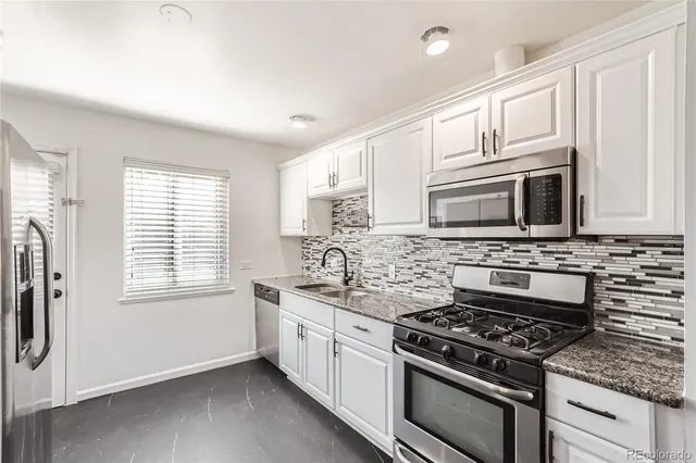 a kitchen with stainless steel appliances granite countertop white cabinets and window
