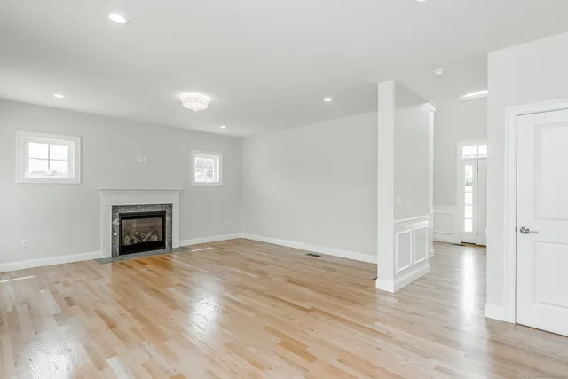 a view of an empty room with wooden floor fireplace and a window