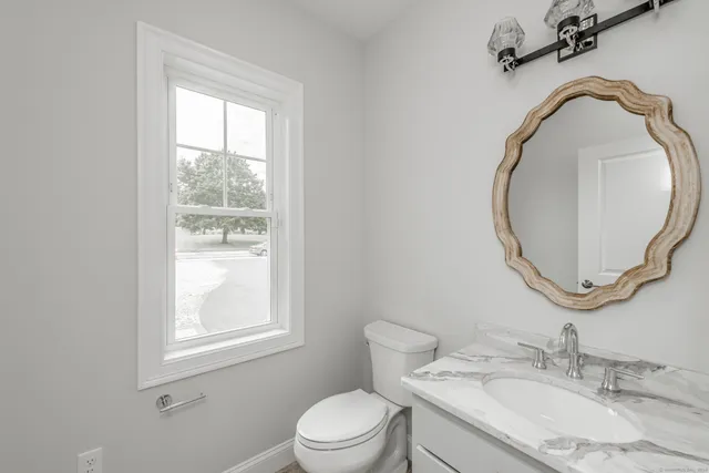 a bathroom with a granite countertop toilet a sink and mirror
