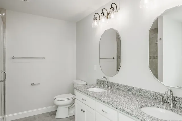 a bathroom with a granite countertop toilet a sink and a mirror