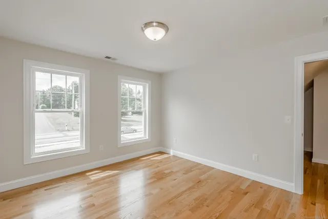 an empty room with wooden floor and windows