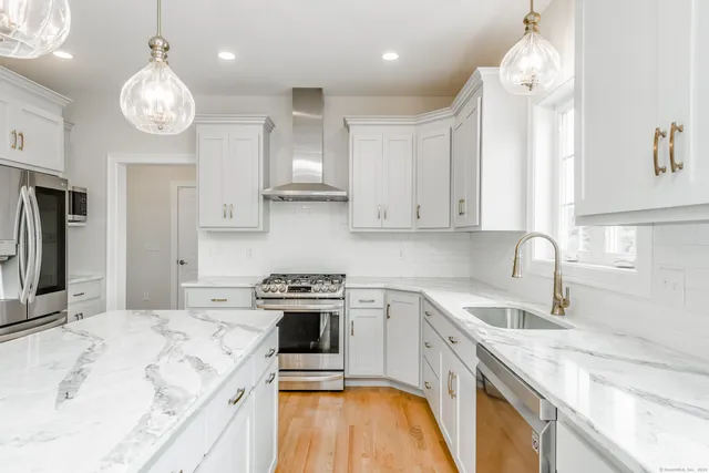 a kitchen with stainless steel appliances granite countertop a sink a stove and a refrigerator