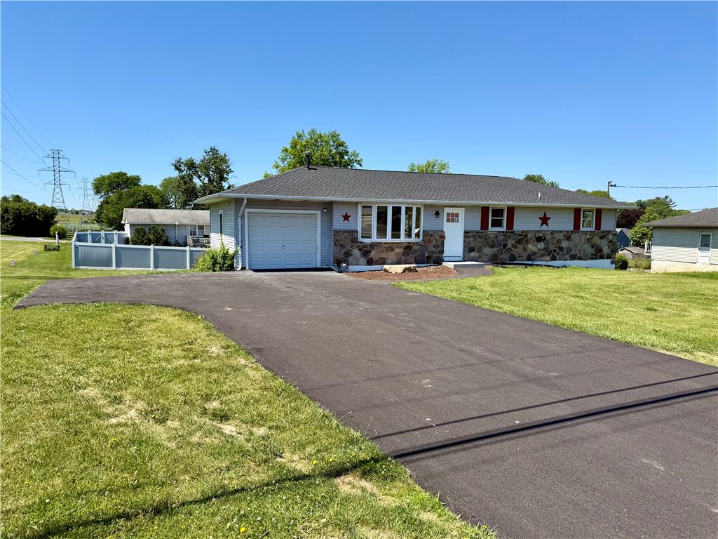 A fully renovated ranch home featuring a fresh driveway and inviting front yard.