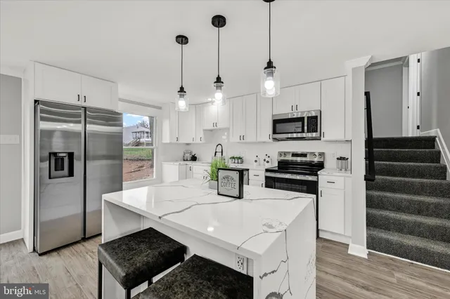a kitchen with stainless steel appliances a sink a stove a refrigerator and cabinets