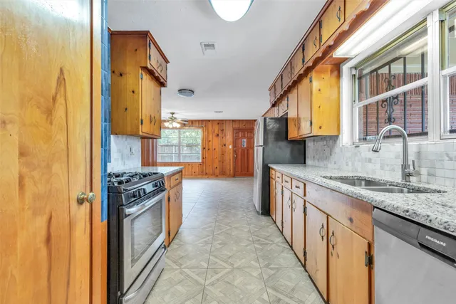 a kitchen with stainless steel appliances granite countertop a stove a sink and a refrigerator