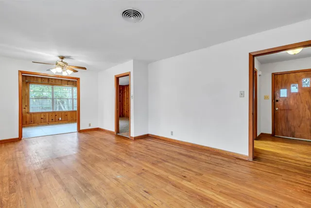 a view of empty room with wooden floor and fan