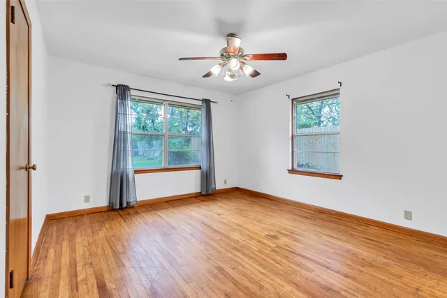 a view of an empty room with window and a ceiling fan