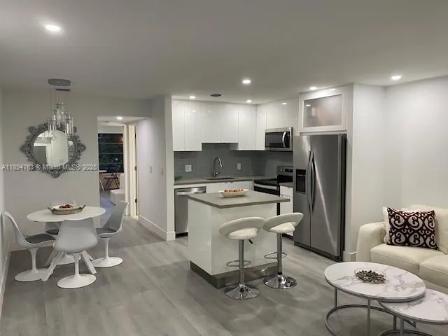 a living room with furniture a refrigerator and kitchen view