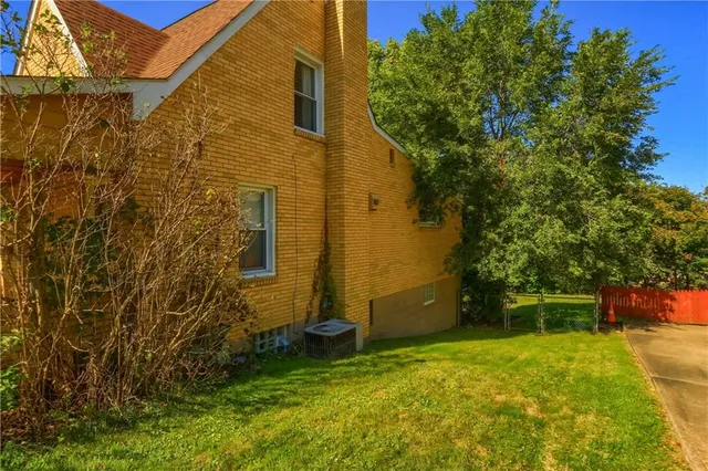 a backyard of a house with plants and large tree