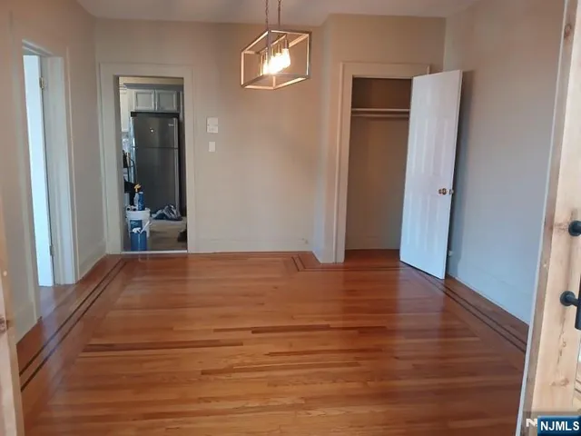 an empty room with wooden floor closet and windows