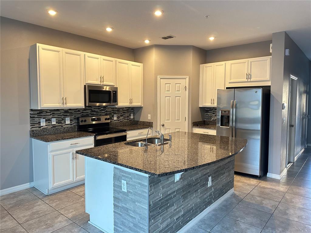 10834 Wyne Tree Orlando, FL 32824 - Photo 3 of 33 a kitchen with stainless steel appliances granite countertop a sink a stove and a refrigerator