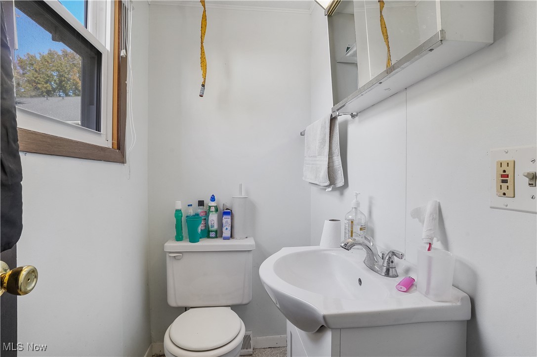 944 Pheasant Run Road Akron, OH 44305 - Photo 8 of 14 Half bathroom featuring vanity, toilet, and ornamental molding