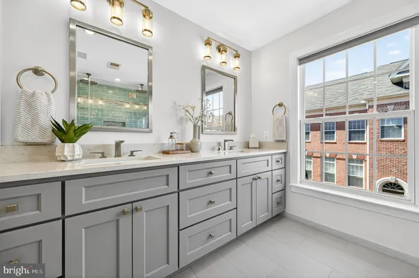 a spacious bathroom with double vanity a mirror a window and vanity