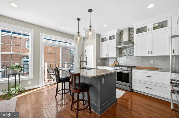 a kitchen with stainless steel appliances granite countertop a stove a refrigerator a kitchen island a table and chairs in it