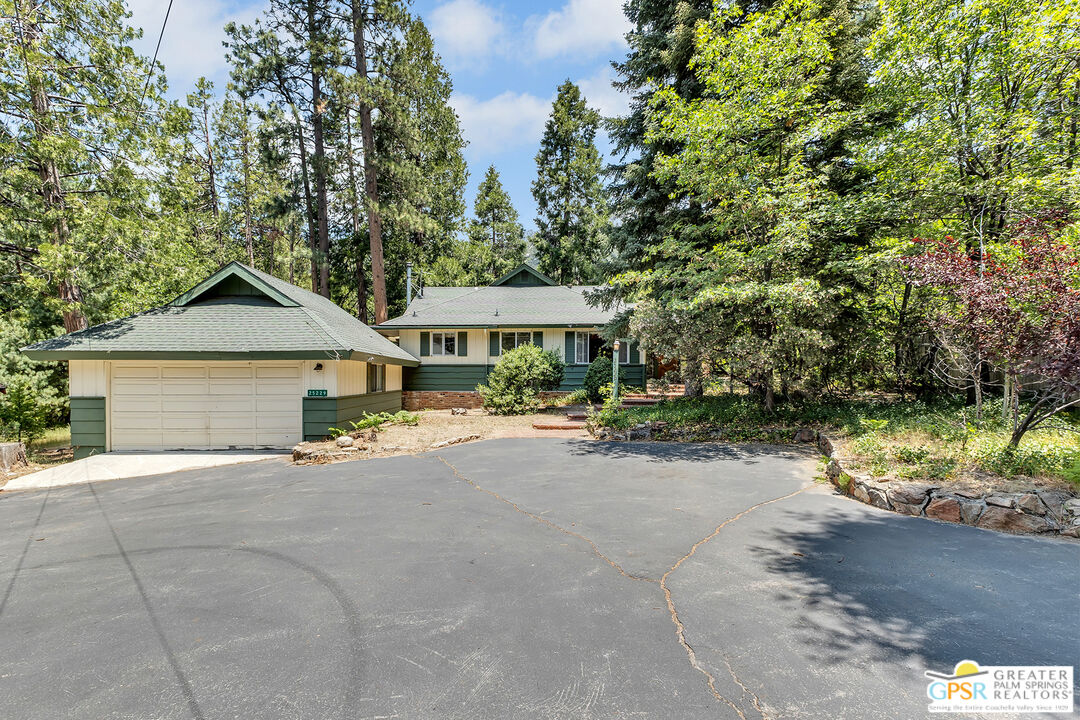 a view of a house with a yard and large trees