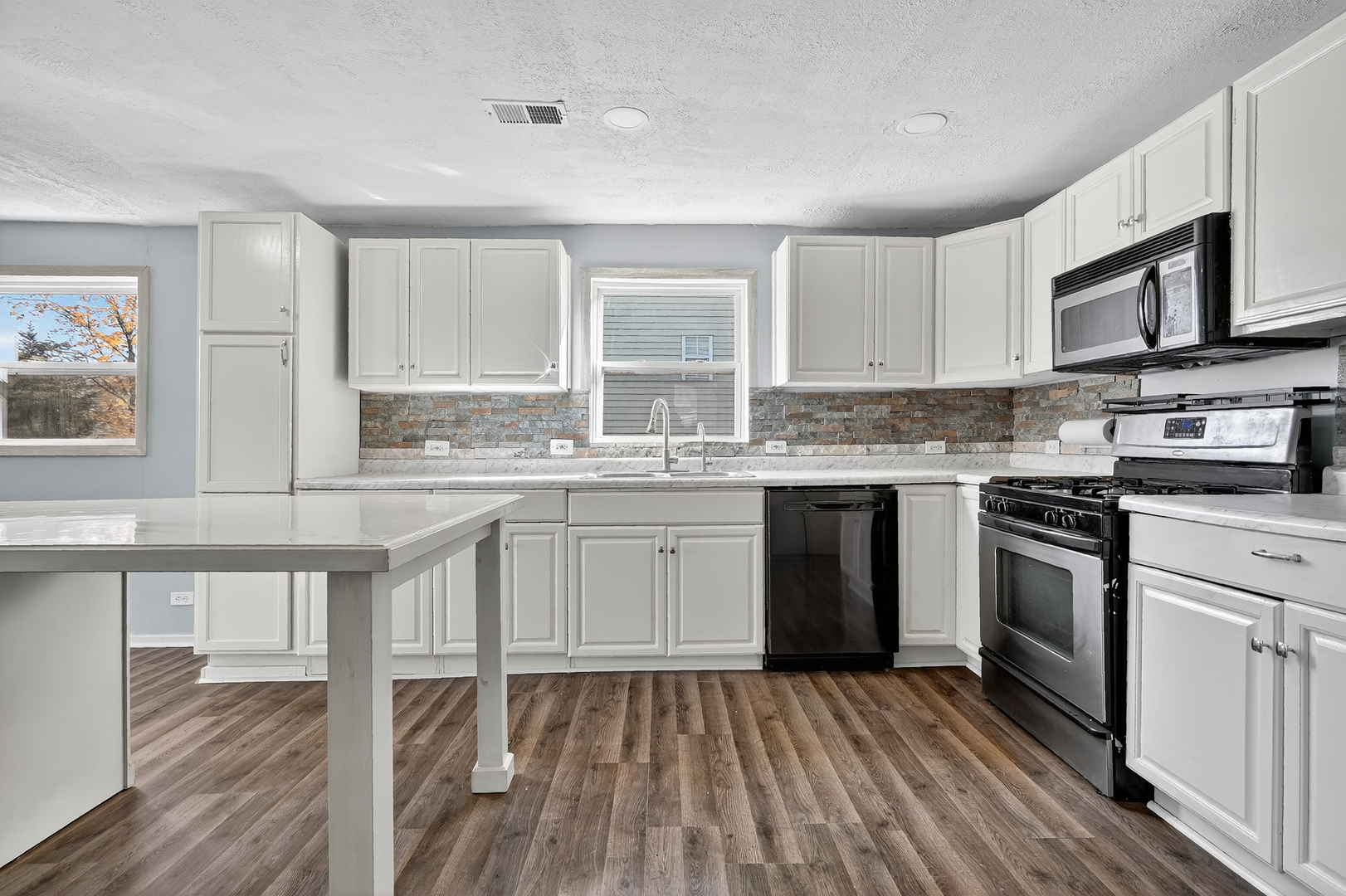 26427 West Prospect Avenue Antioch, IL 60002 - Photo 5 of 22 a kitchen with stainless steel appliances granite countertop a stove top oven a sink dishwasher and white cabinets with wooden floor