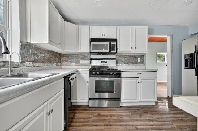 a kitchen with stainless steel appliances granite countertop a stove a sink and a microwave