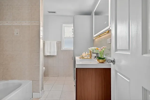 a view of bathroom with a sink mirror and window